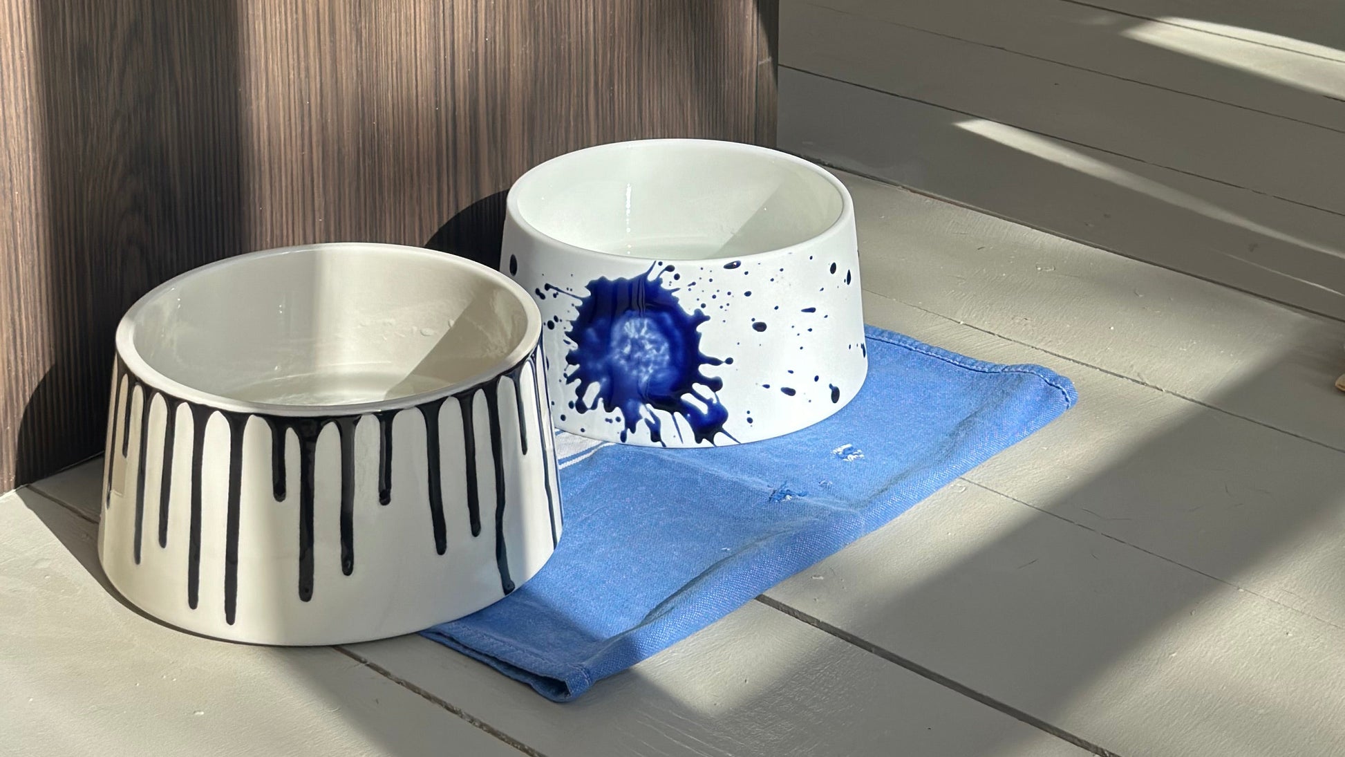 Two ceramic bowls with abstract designs on a wooden surface.